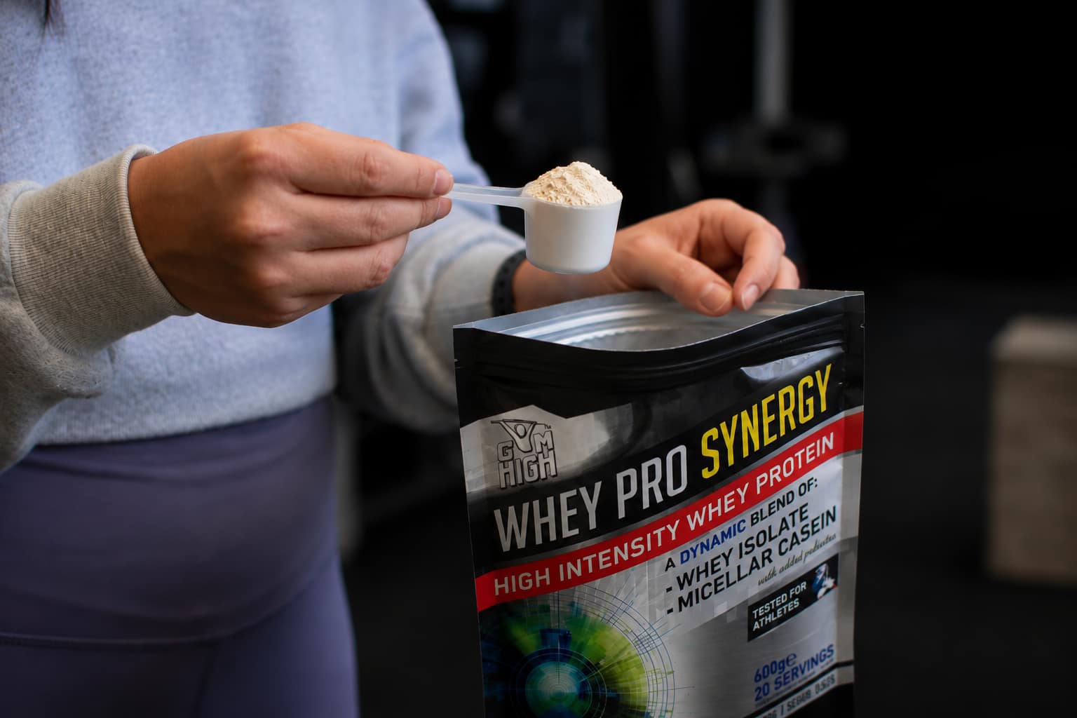 closeup of the hands af an athlete pouring a protein from the bag